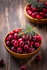 Ripe organic cranberries in wooden bowl on wooden background