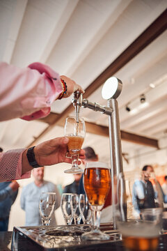 Mans hand pouring pint of beer behind the bar