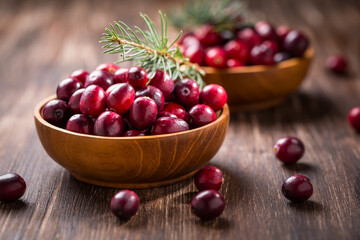 Ripe organic cranberries in wooden bowl on wooden background