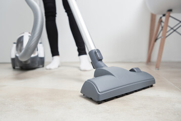 Woman use vacuum cleaner at the floor
