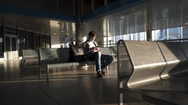 Waiting for flight at an empty airport. Man sitting on chair in empty airport lounge. Flights canceled. Problems with flights during quarantine. The collapse of airlines. Covid 19, coronavirus