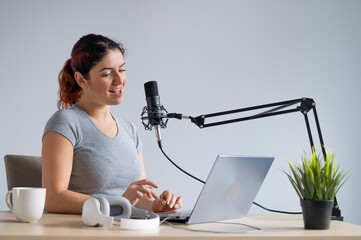 A charming woman radio host is broadcasting live on a laptop. Online radio concept