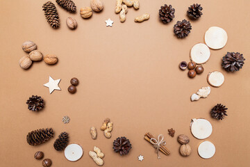 Fototapeta na wymiar Festive Christmas composition in eco style of fir and pine cones, walnuts, macadamia, peanuts, cinnamon sticks and wooden decorations on a beige background.Christmas ornament with space for text flat 