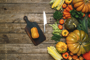 Wooden cutting board with autumn vegetables on wooden table