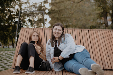 Fototapeta premium Two young adult girls on a sunbed in a city Park