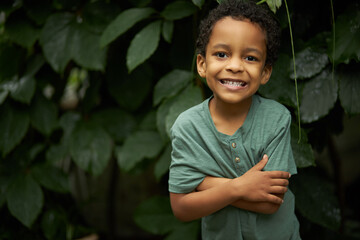 portrait of adorable black child boy near plants, african kid boy look at camera and smile, in the...