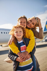 Fototapeta na wymiar Smiling siblings with their mother close to an aircraft