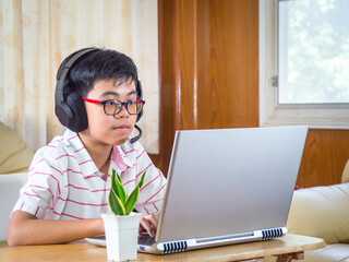 The boy wearing headphones sitting at the table with internet chat skype teacher prepare for exam...
