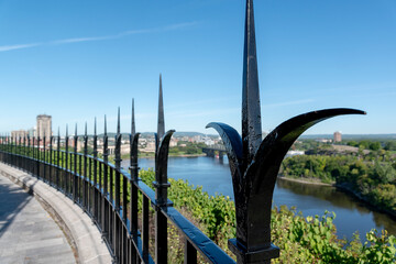 An old, black, iron decorative fence behind the Canadian Parliament Building prevents tourists from...