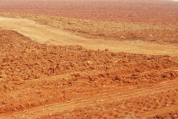 Plowing in arid planting field. Red brown soil of infertility farmland.