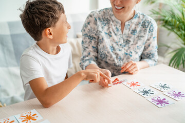 7-year-old boy plays a memory Board game with his mother to develop memory