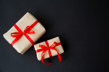 Gift boxes tied with red ribbons on a black background, Christmas decoration, gift wrapping. Top view with copy space