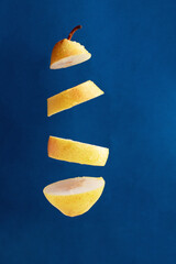 floating pieces of yellow pear against blue background, creative picture
