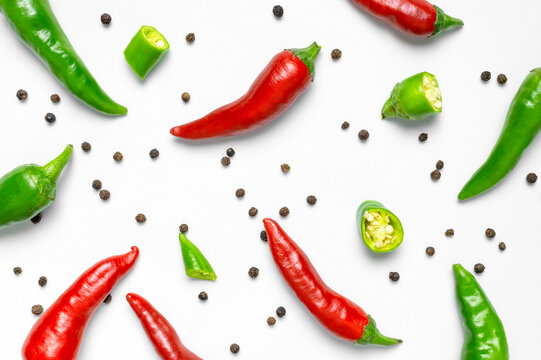Hot red and green fresh chili peppers, dry black peppercorns on white background flat lay top view. Seasoning for dish, spicy spices for cooking, cayenne pepper, food. Creative layout, chili pattern
