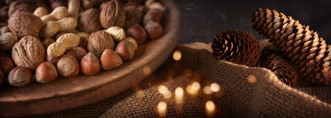 Mixed nuts at christmas time
Mixed nuts at christmas time on rustic background with golden bokeh. Healthy snack with walnuts, peanuts and hazelnuts in a wooden bowl. Short depth of field. - obrazy, fototapety, plakaty