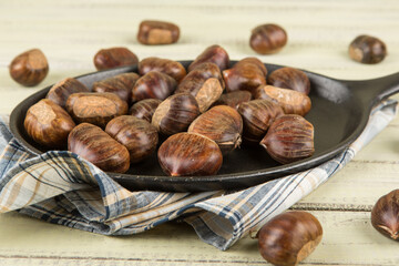 Chestnuts in a pan on a wooden background. Rustic style