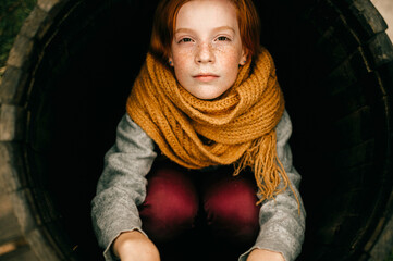 Young girl siiting in a wood barrel