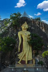 Golden standing buddha statue on the cliff at Khao Hin Ngoo Moutain Rock Park ( Snake mountain),  Ratchaburi province, Thailand. This is  public property, no restrict in copy or use.