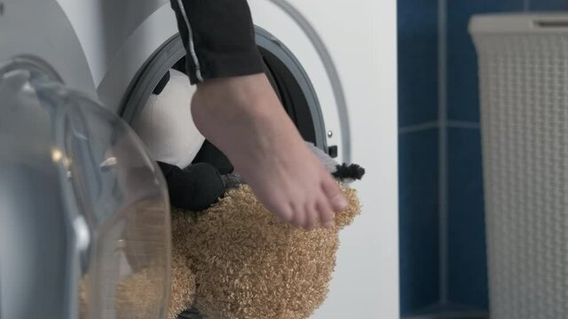 Clean toys from machine. The child's feet dangle over the clean inserts in the washing machine.