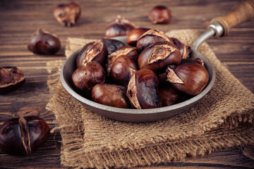 Chestnuts in a pan on a wooden background. Rustic style