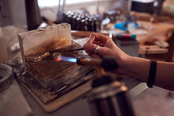 Close Up Of Male Jeweller Working On Ring With Blowtorch In Studio - obrazy, fototapety, plakaty