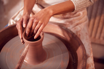 Close Up Of Female Potter Shaping Clay For Pot On Pottery Wheel In Ceramics Studio