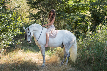 Attractive female riding a horse through the farm
