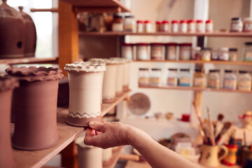 Close Up Of Potter Putting Glazed Clay Vase On Shelf In Ceramics Studio