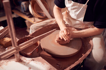 Close Up Of Female Potter Shaping Clay For Pot On Pottery Wheel In Ceramics Studio