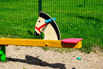 Kolorowa, drewniana huśtawka w kształcie konia na placu zabaw