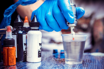 Hand of a tattooer, holding a tattoo gun.