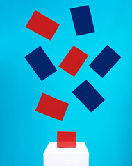 election concept - blue and red cards fall into a white voting box with a slot, the background is blue, levitation