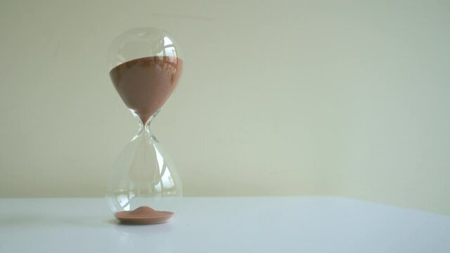Hourglass on white table and countdown, sand falls, time is go away