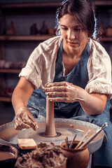 Stylish professional potter demonstrates the process of making ceramic dishes using the old technology. Concept for woman in freelance, business, hobby.