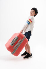 Asian kid boy holding big red luggage that looking heavy over the white background. Travel season.