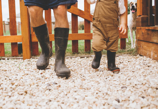 Father and son walking in irrigation boots in backyard garden