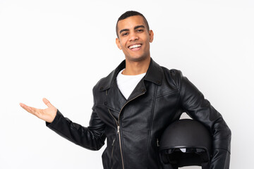 Young handsome man with a motorcycle helmet over isolated white background holding copyspace imaginary on the palm