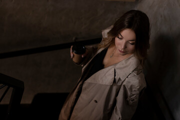 sensual attractive brunette in trench coat in dark loft room. urban lifestyle concept.