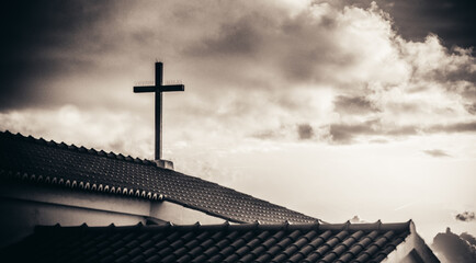 cruz cristiana en el techo de una iglesia portuguesa en carboeiro con un cielo nublado.
monocroma.