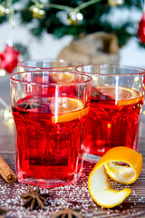 Close-up of three glasses of hot mulled red wine, on a wooden table with a Christmas tree in the background. Typical Christmas drink. Homemade Christmas concept. Vertical photography