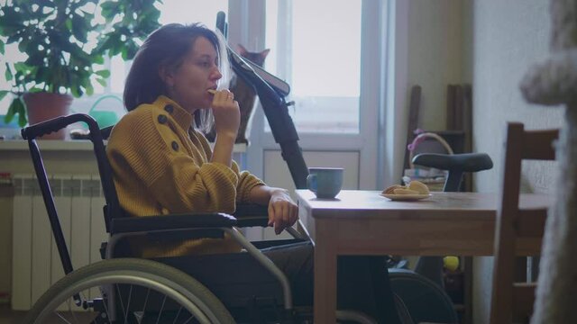 Woman in wheelchair drinks tea at home