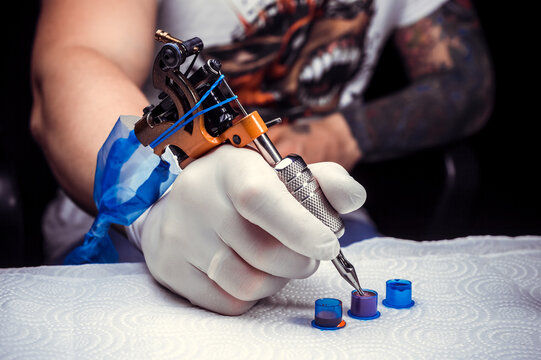 Hand of a tattoo artist and a tattoo gun.