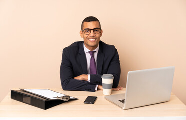 Young business man in his office with a laptop and other documents keeping the arms crossed in frontal position
