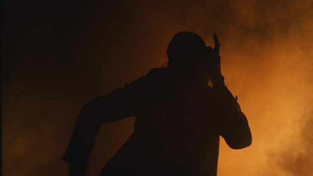 a man dancing in the smoke and spotlight