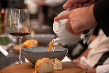 Obraz na płótnie Canvas Butler pouring soup for the guest