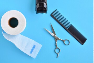 Clipper and hairdressing scissors and comb on background. Hairdresser tools with selective focus on blue  background. 
