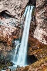 Fototapeta na wymiar White and blue waterfall inside the rocks and stones