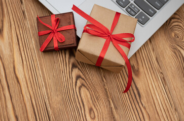 Online shopping for christmas, gift boxes with red ribbon, laying next to a laptop on a wooden...