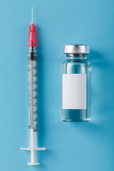 Ampoule with a vaccine and a syringe for viruses and diseases on a blue background.