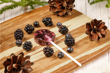 Homemade lollipops made from natural dehydrated bilberry and blackberries on a white wooden background. Healthy vegan vegetarian food with no sweets.